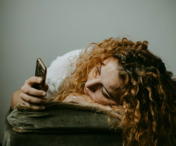Woman with dating app burnout lying down while holding her phone